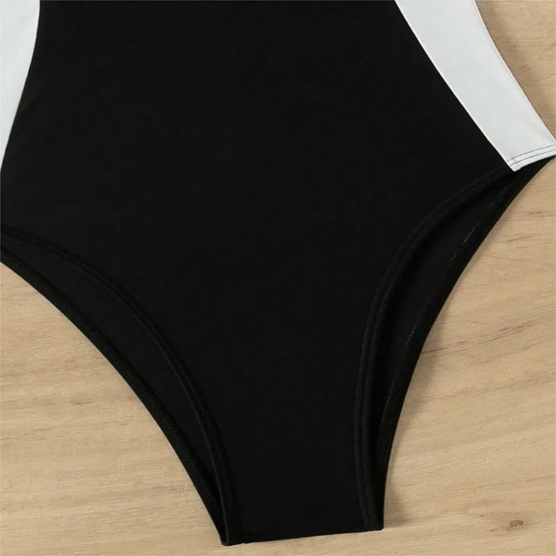 Black and white women's one-piece swimsuit with pearl spaghetti straps, shown on a model.