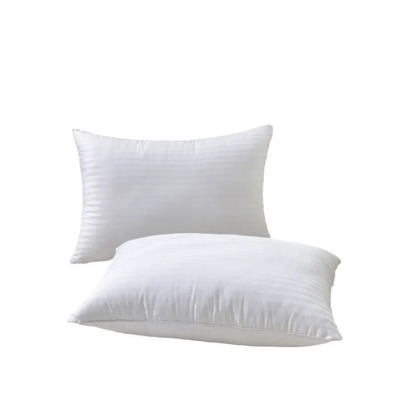 White cotton satin stripe pillow with feather and cotton filler on a bed.