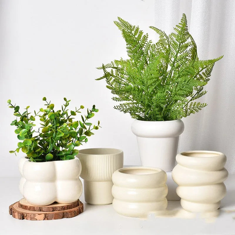 Matte yellow ceramic flower pot with a Roman column design on a table.