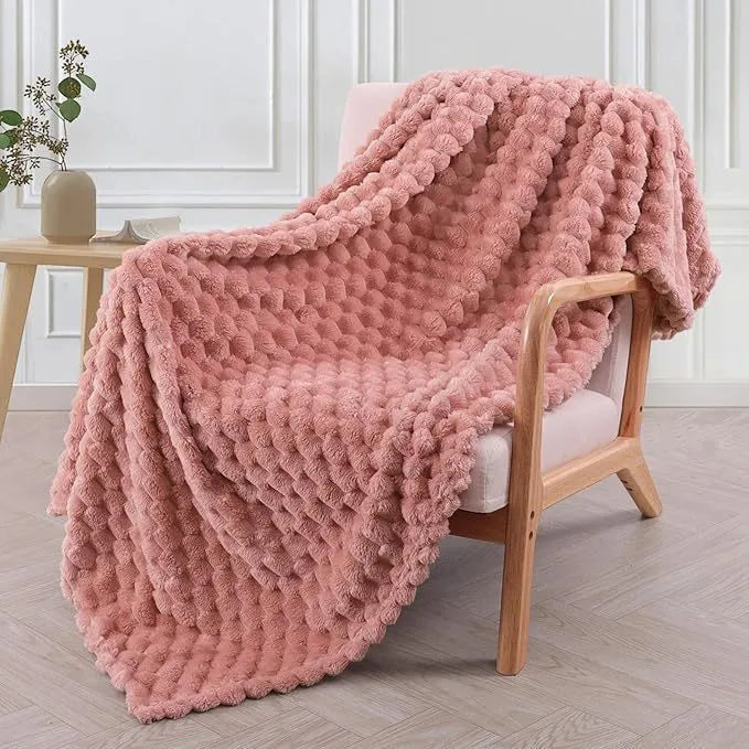 Soft camel-coloured plaid fleece blanket for children folded on a bed.