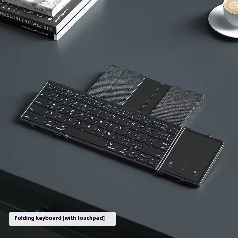Black folding Bluetooth keyboard with touchpad option next to a mobile phone