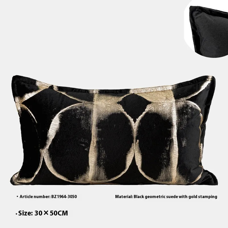 Black and gold abstract pattern decorative velvet cushion on a grey sofa.