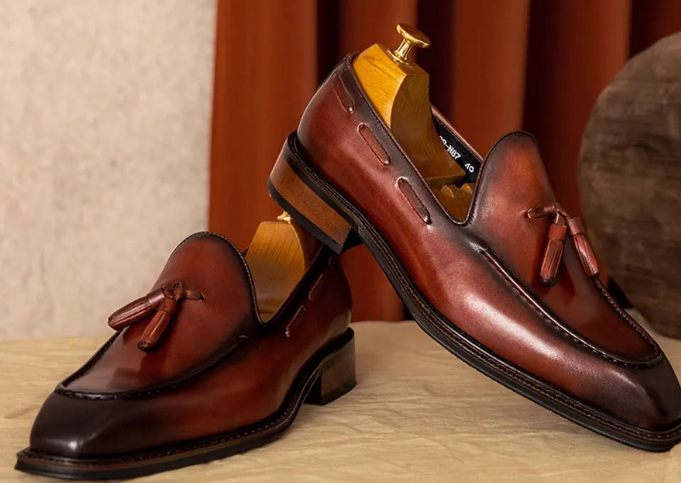 Men's black and brown genuine leather slip-on loafers with a polished finish and rubber sole.