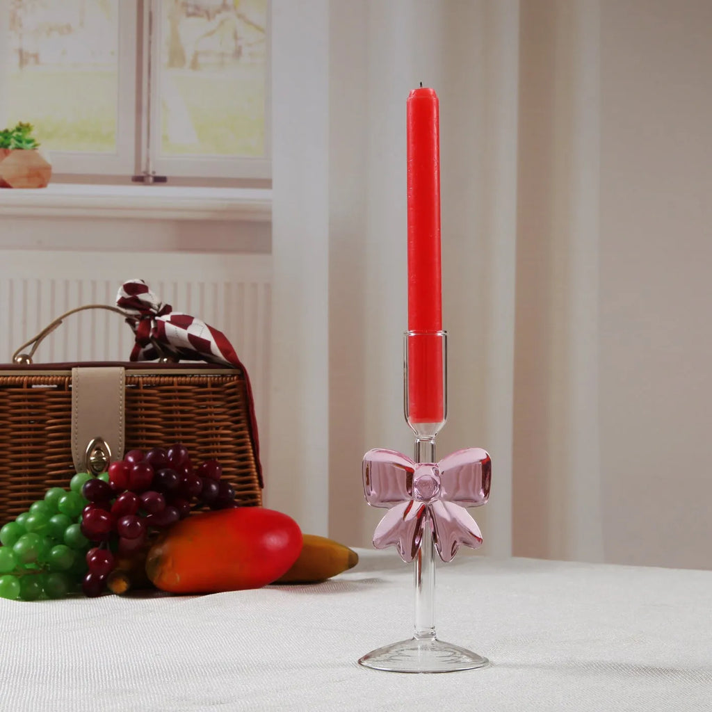 Set of three clear borosilicate glass candlesticks with large bow decorations on a table