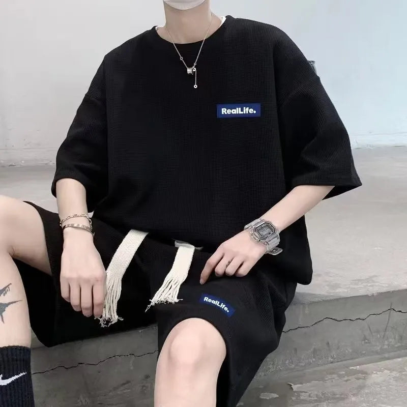 Man wearing a grey waffle-textured short sleeve top and matching shorts leisure set.