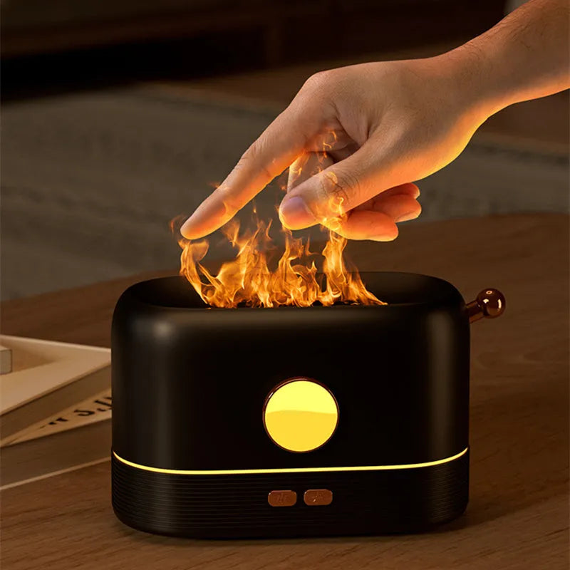 Black USB desktop humidifier with decorative orange flame effect and water tank on a wooden desk.