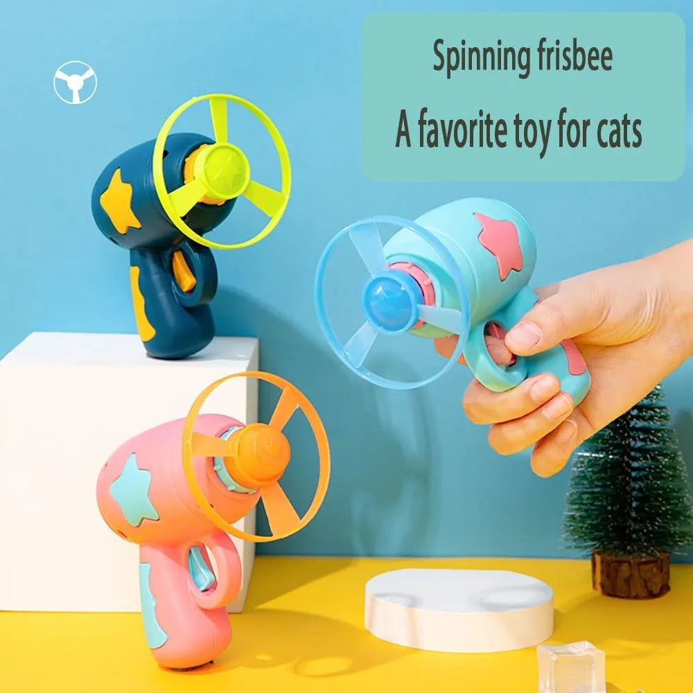 Blue plastic cat toy gun launcher with a mounted orange Frisbee, shown next to a second green Frisbee.