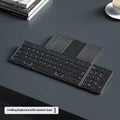 Black folding Bluetooth keyboard with touchpad option next to a mobile phone