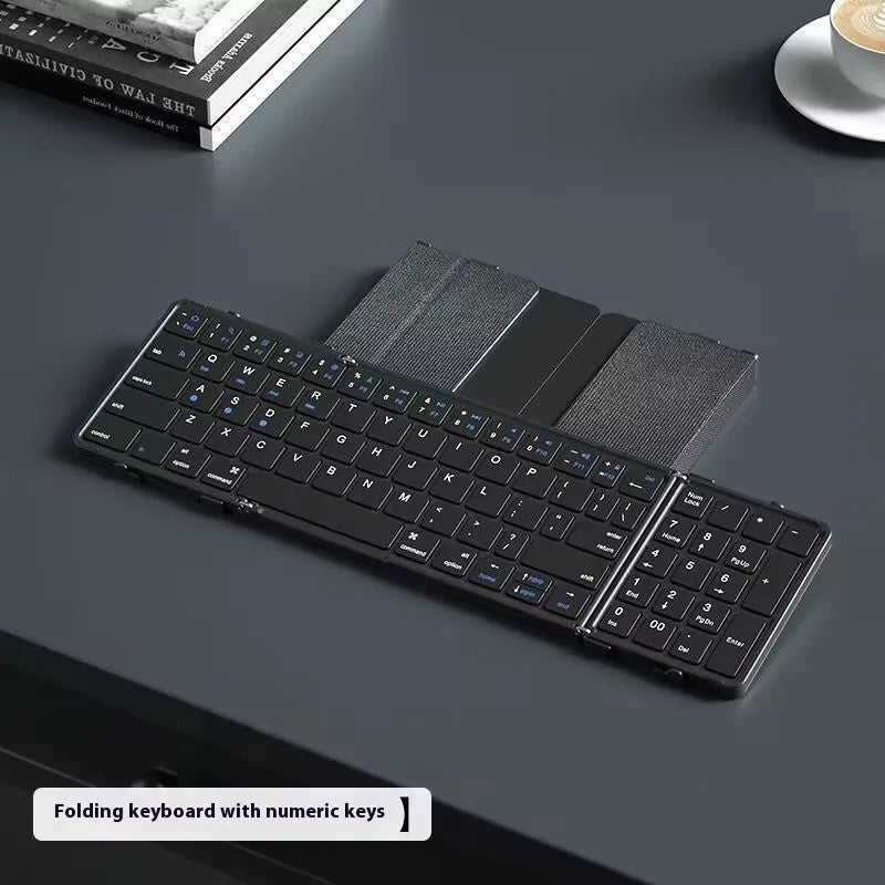 Black folding Bluetooth keyboard with touchpad option next to a mobile phone