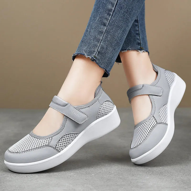 Women's low-top grey mesh sneakers with Velcro straps on a flat polyurethane sole.
