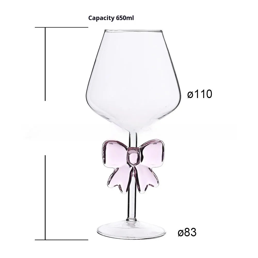 Set of three clear borosilicate glass candlesticks with large bow decorations on a table