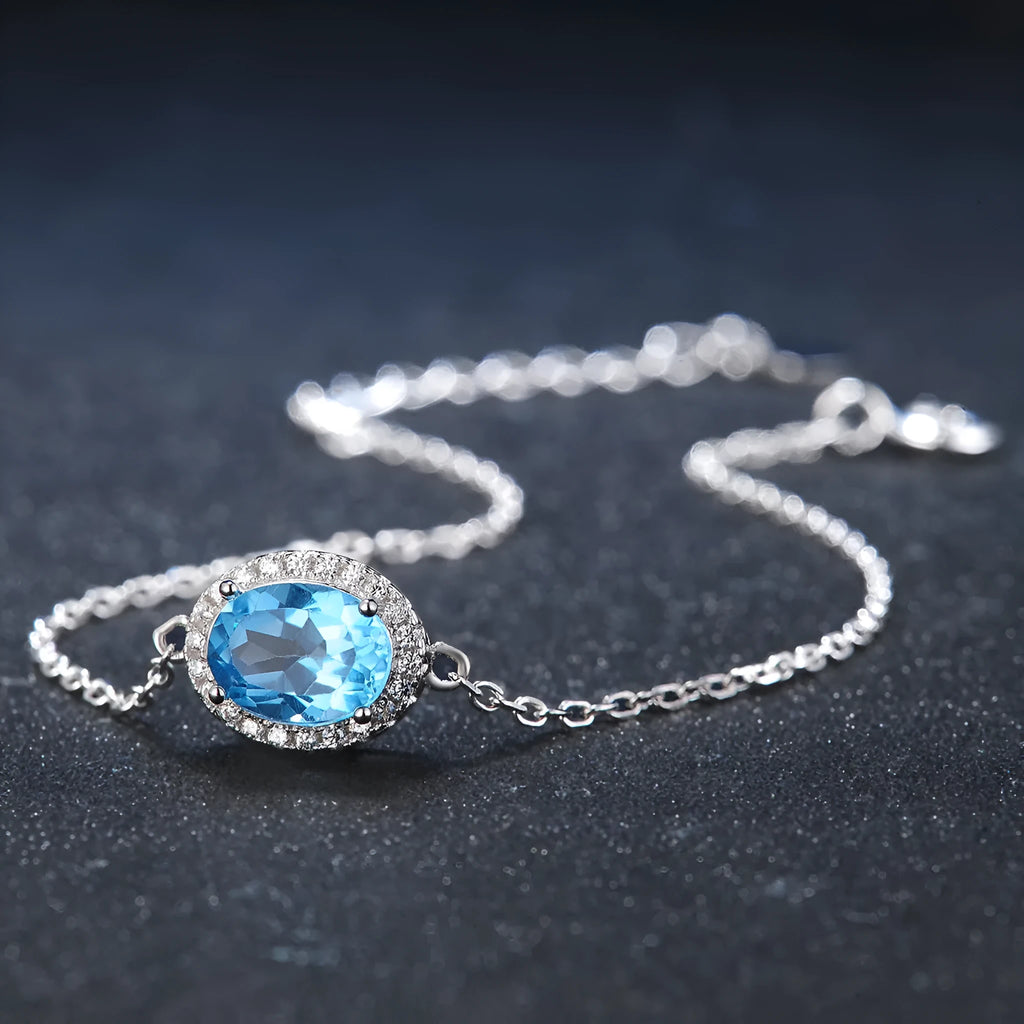 Four-piece 925 sterling silver jewellery set with blue topaz gemstones in a geometric design, showing earrings, ring, pendant and necklace.