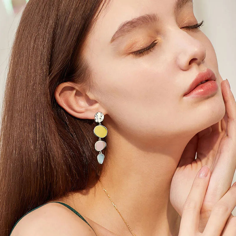 A pair of thin sterling silver stud earrings with Morandi-coloured wafer discs featuring an oil-drip texture.