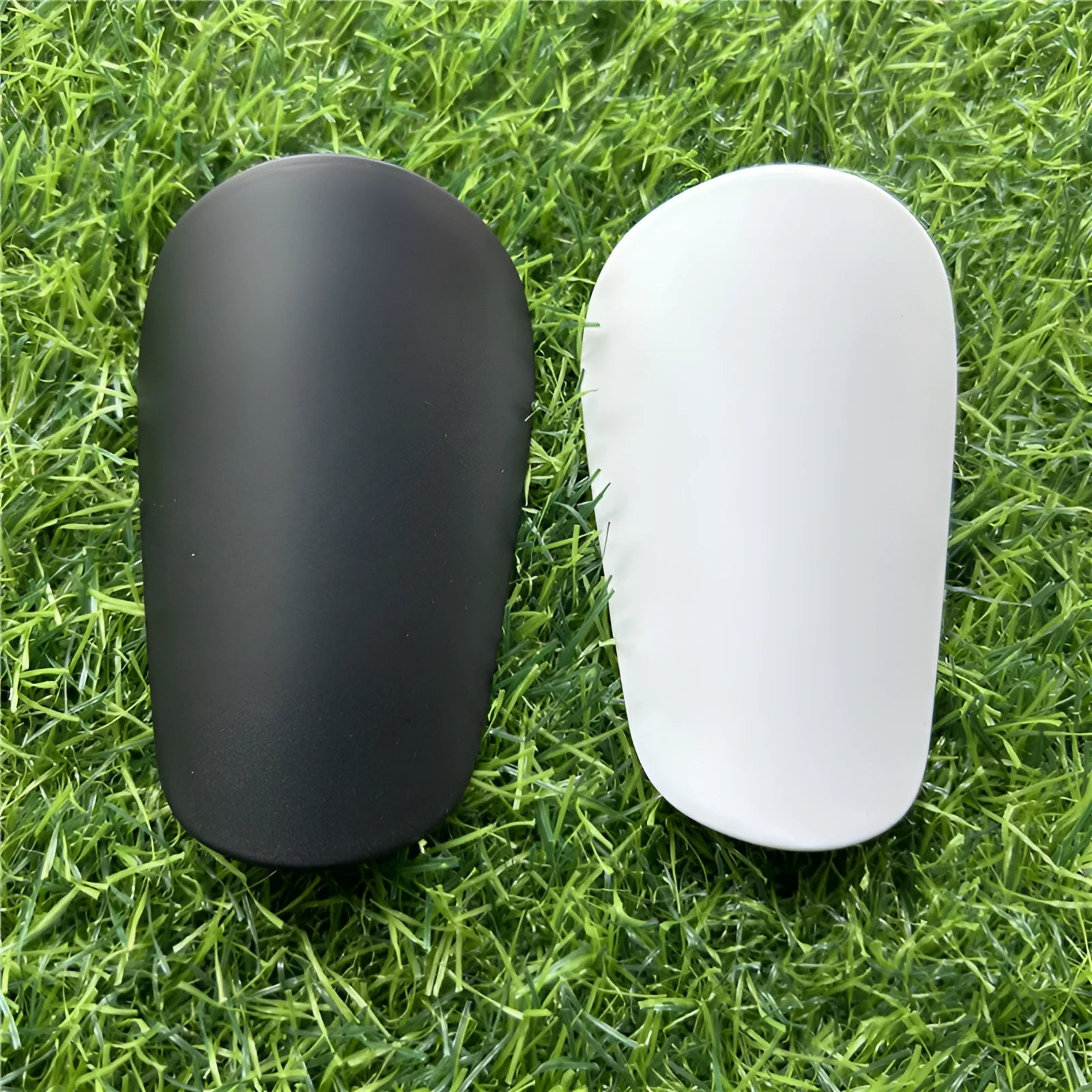 Extra small mini football shin guards in black and white colours measuring 8cm by 5cm