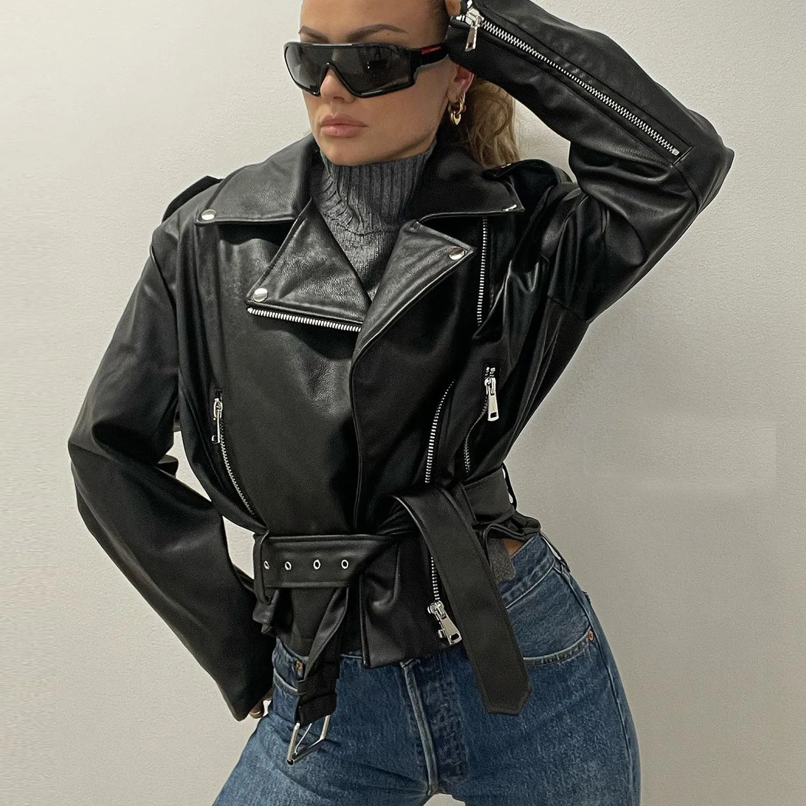 A black punk-style jacket with a lapel, short belt, and Peter Pan collar on a hanger.