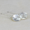 Women's round silver earrings with glossy finish showing bird and flower retro designs