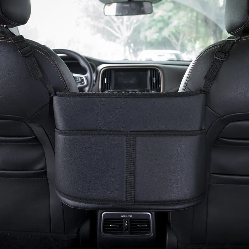 Black leather car interseat storage bag holding a tissue box, hanging between vehicle front seats.