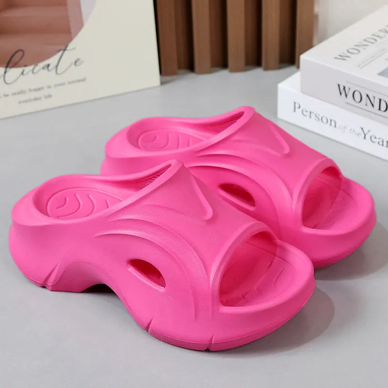 Women's thick-soled EVA slippers in rose red colour on a sandy beach.
