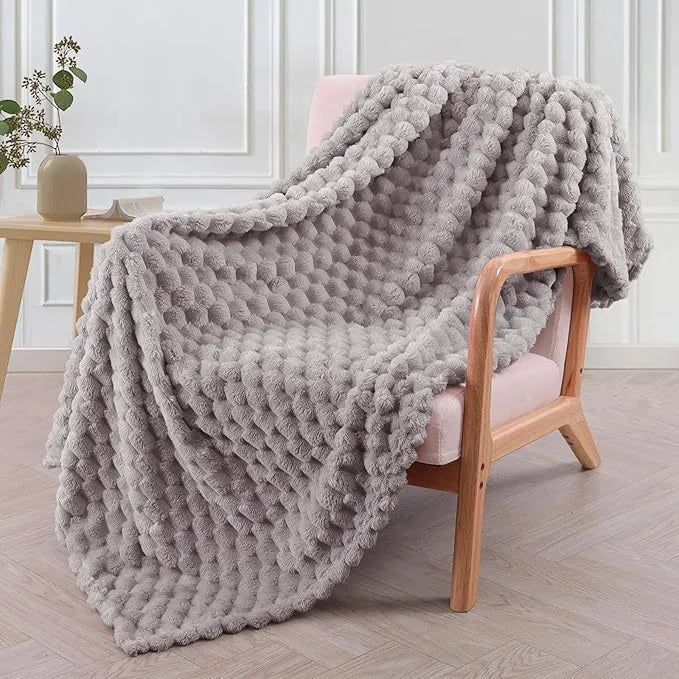 Soft camel-coloured plaid fleece blanket for children folded on a bed.