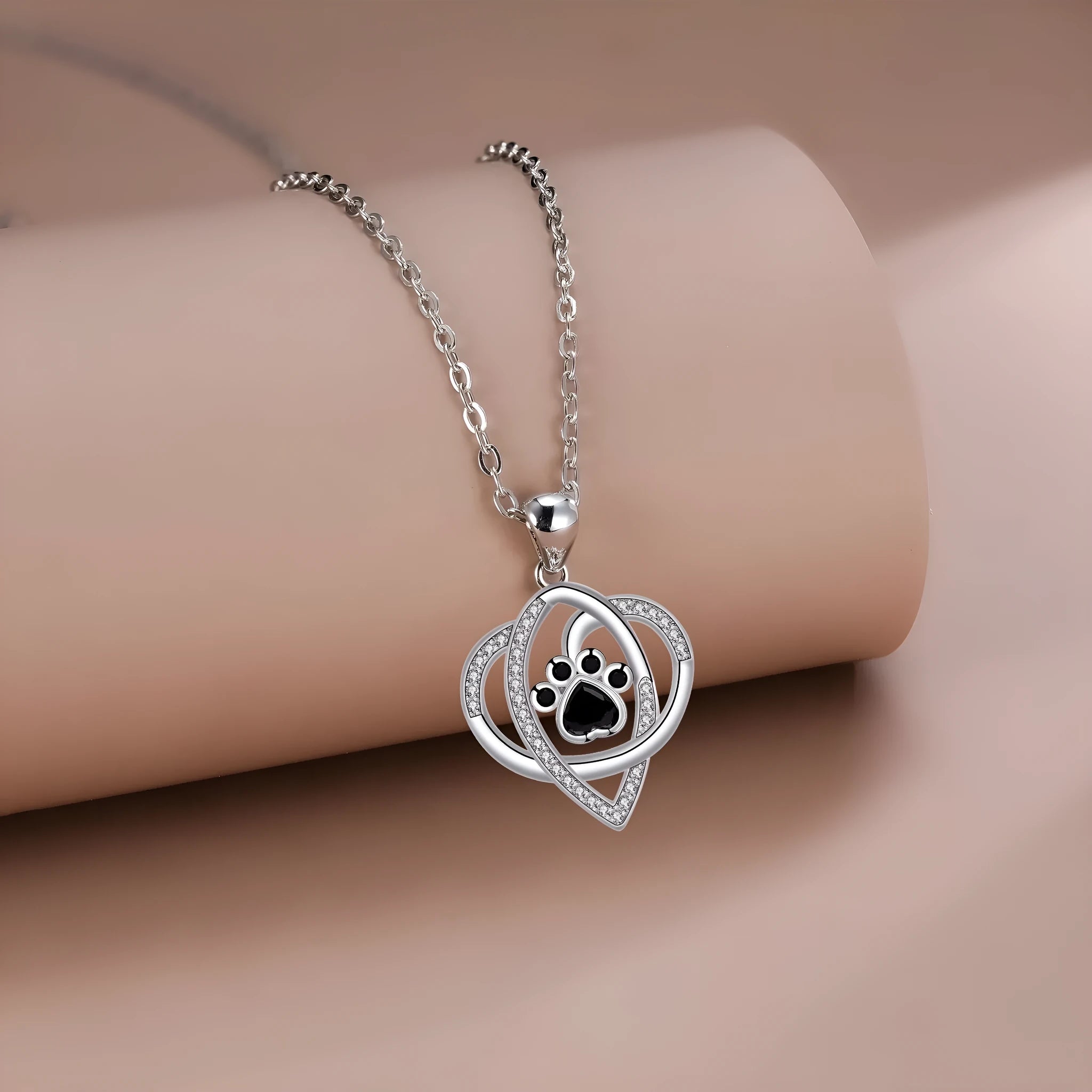 Close-up of a women's copper necklace with a dog paw print pendant on a cross chain.