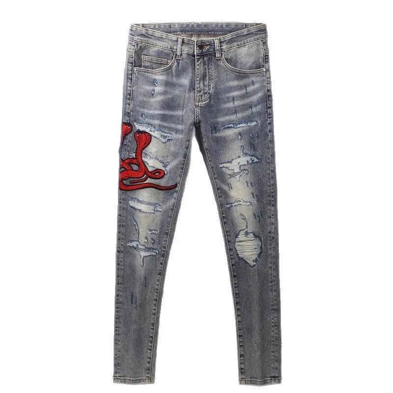 Men's old colour slim fit jeans with worn-out patches, holes, and embroidery on the legs.
