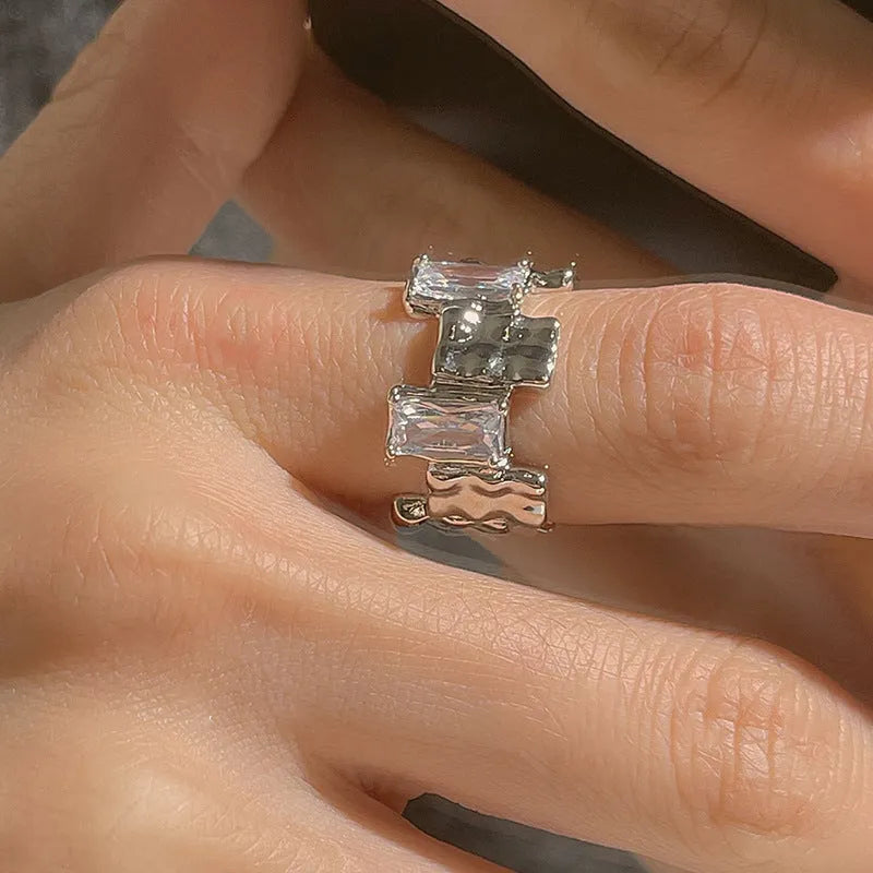 Silver geometric open ring with cross design and zircon decoration on white background