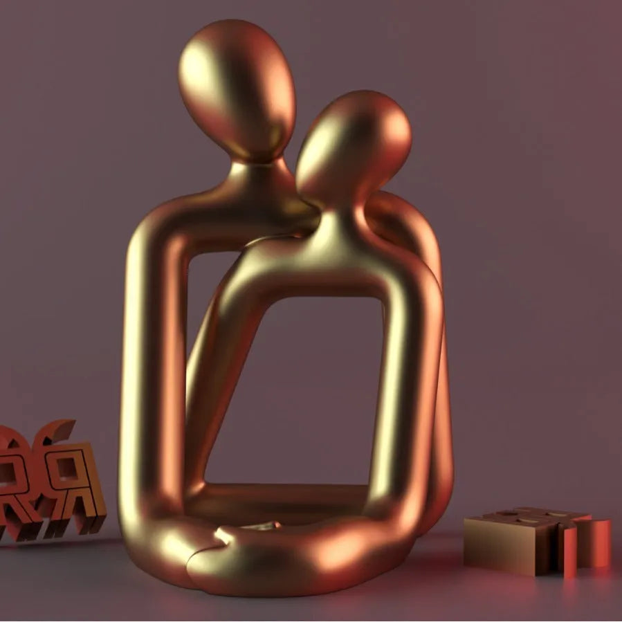 Modern style resin statue of a couple in milky white or gold colour on a wooden surface.
