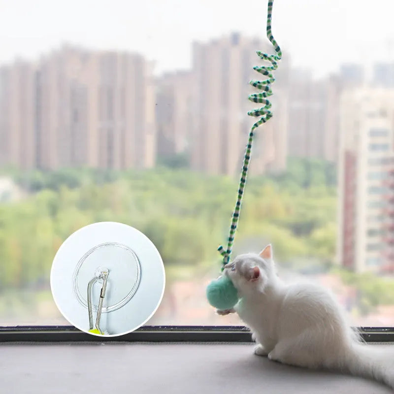 Colourful spring cat toy with hanging bell stick and inflatable ball, shown with a white suction cup.