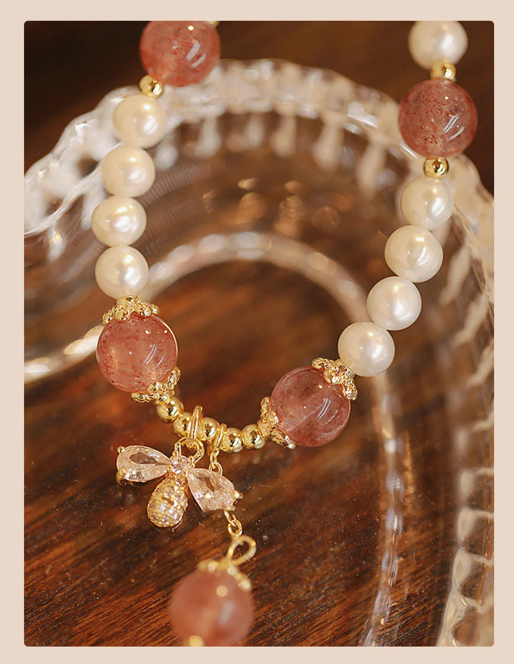 Women's strawberry quartz crystal bracelet with pearls and bow charm on wrist