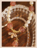 Women's strawberry quartz crystal bracelet with pearls and bow charm on wrist