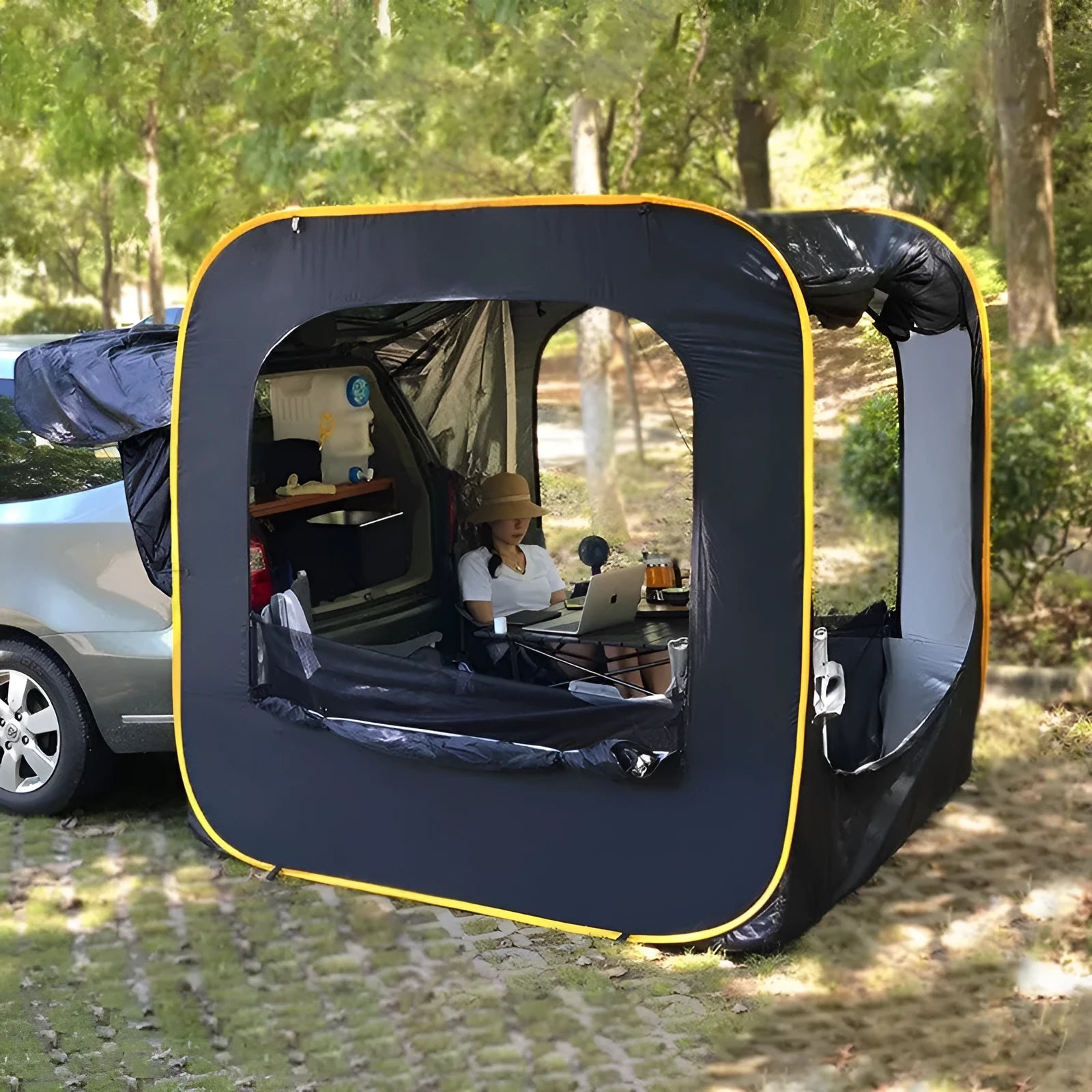 Black pop-up tailgate tent unfolded next to a car, showing its cubic 200cm shape and quick-throw design.
