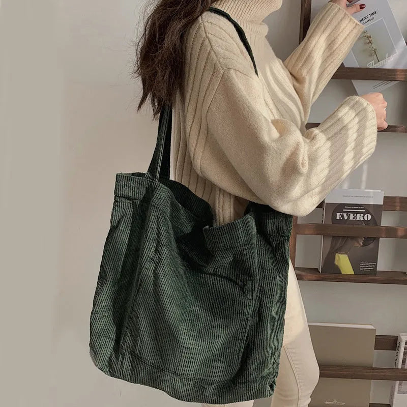 Large corduroy tote bag with soft handle, pleated detailing, and interior zipper pocket. Colour: black.