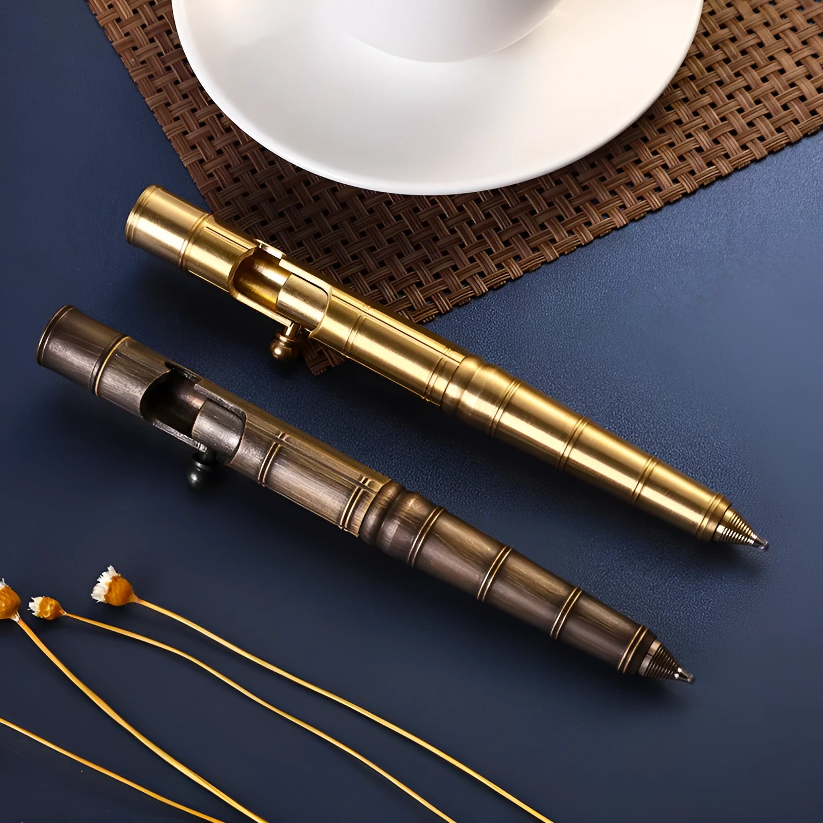 Close-up of a solid brass bolt action tactical pen with a press mechanism on a dark surface.