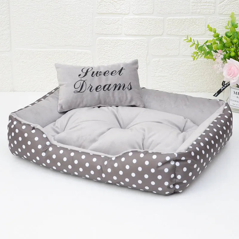 Polka dot print dog bed with matching embroidered cushion in grey, shown in a home setting.