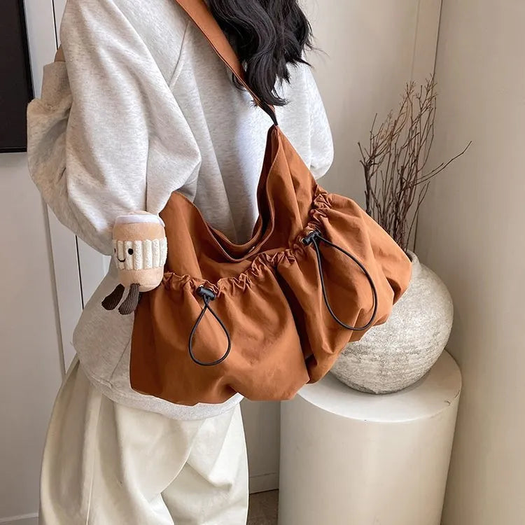 Green pleated crossbody student bag showing foldable polyester construction and internal mobile phone pocket