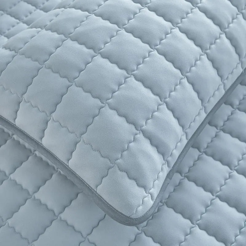 Blue washed cotton fitted sheet with quilted pattern on a bed, showcasing its waterproof protection feature.