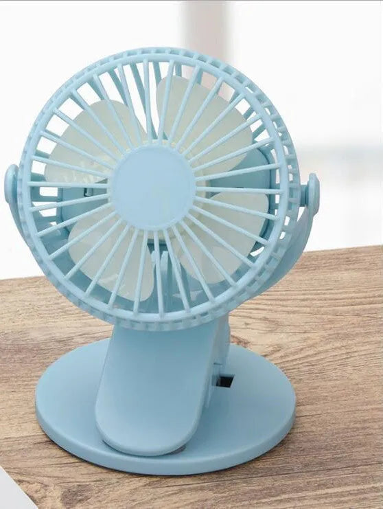 White USB rechargeable mini clip fan attached to a desk edge showing piano button switch and plastic blades.