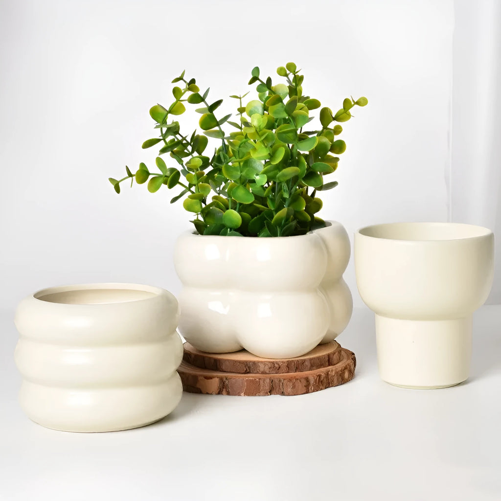 Matte yellow ceramic flower pot with a Roman column design on a table.
