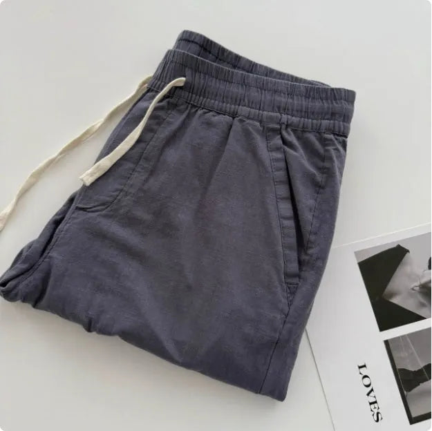 Man wearing beige loose straight leg casual trousers with a drawstring waistband.