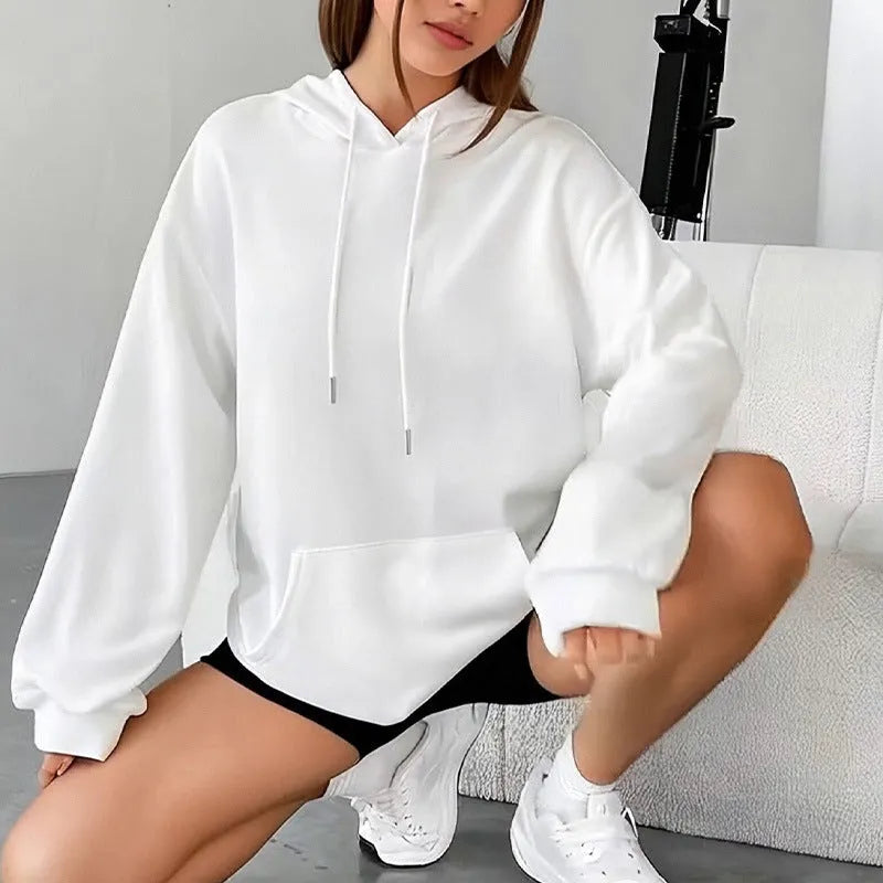 Woman wearing a loose-fitting black hooded sweatshirt with a front kangaroo pocket.