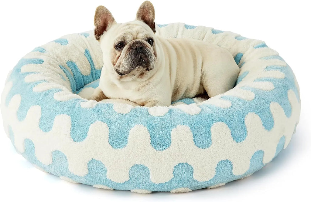 Round plastic dog bed with a blue and white plaid fabric cover, shown on a wooden floor.