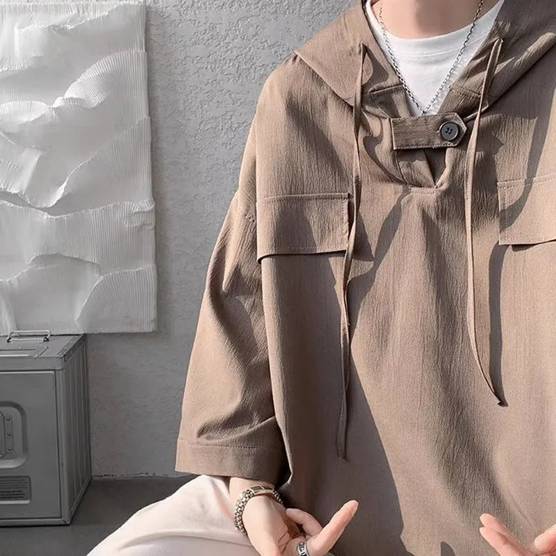 A man wearing a loose-fit black hooded short sleeve t-shirt made of polyester for summer.