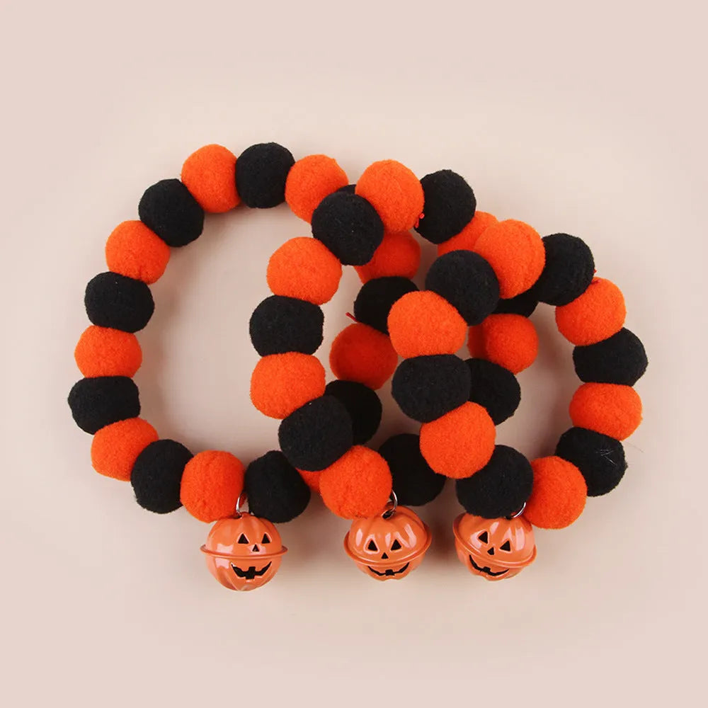 Orange Halloween cat collar with 'Naughty Cat' text and a detachable plastic pumpkin charm on a table.