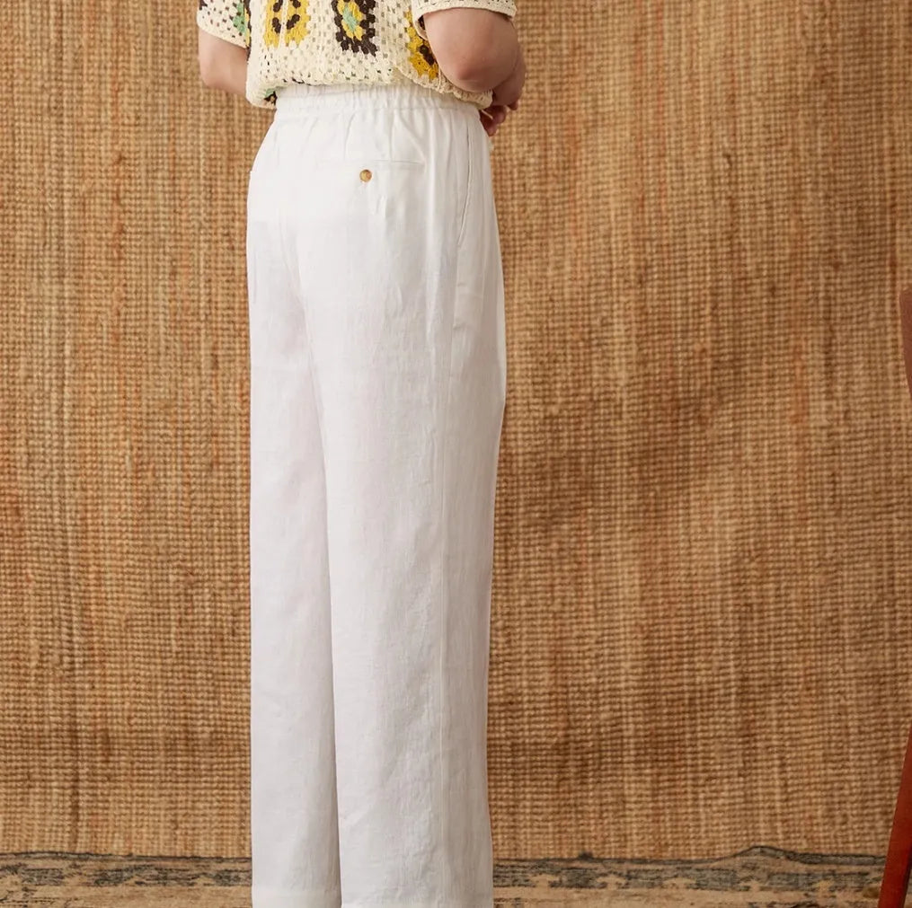A pair of loose-fit, high-waisted linen trousers in a neutral colour with an elasticated waistband and straight legs.