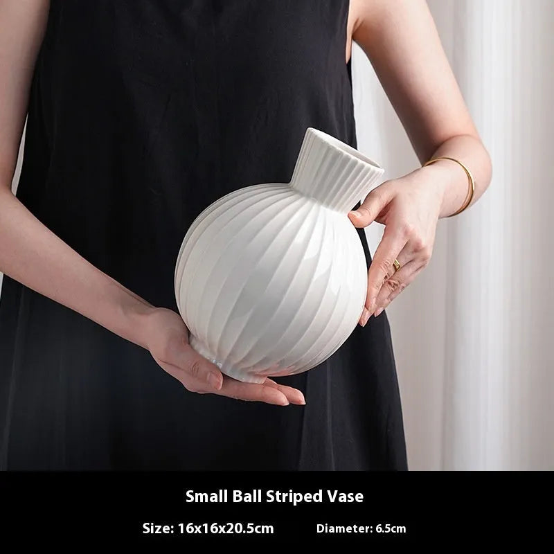 White ceramic ball vase with striped patterning in American country style on wooden table