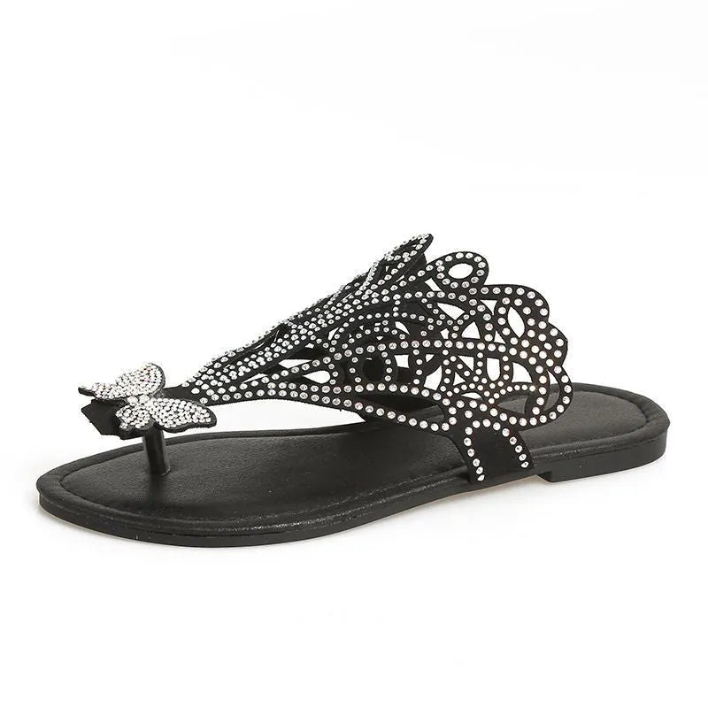 Women's black slip-on sandals with rhinestone detail, hollow-out design, and flat rubber sole.