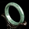 A simple deep pea green women's bracelet shown with a gift box and certificate.