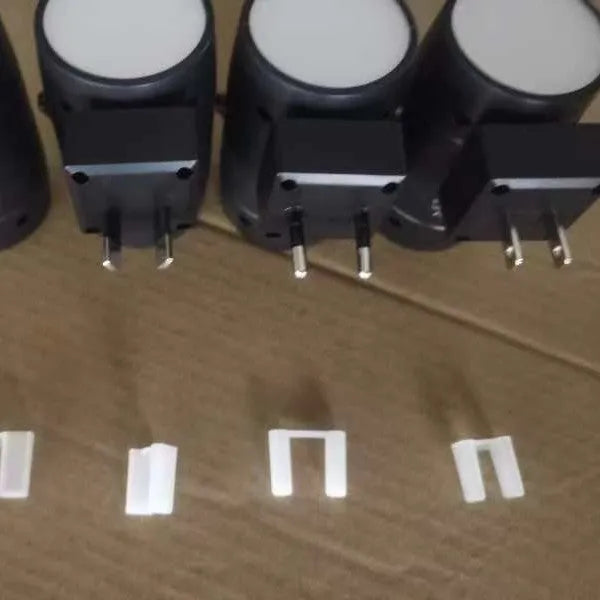 White plug-in adjustable night lamp with a rotatable light head, shown next to a power socket.