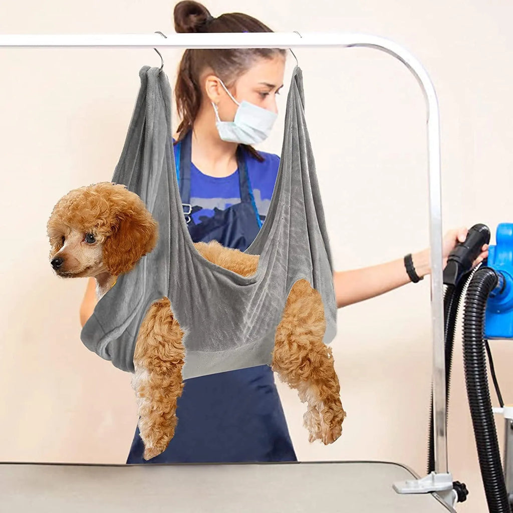 Pet grooming hammock harness in pink with double-layer flannel fabric and reinforced grommets, showing a dog suspended comfortably