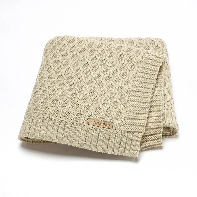 Solid colour infant blanket with textured lines, shown in a choice of colours including pink and beige.